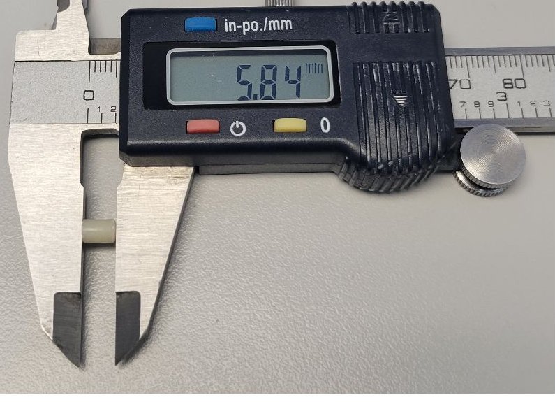 A digital caliper measuring a cured composite specimen at 5.84 mm