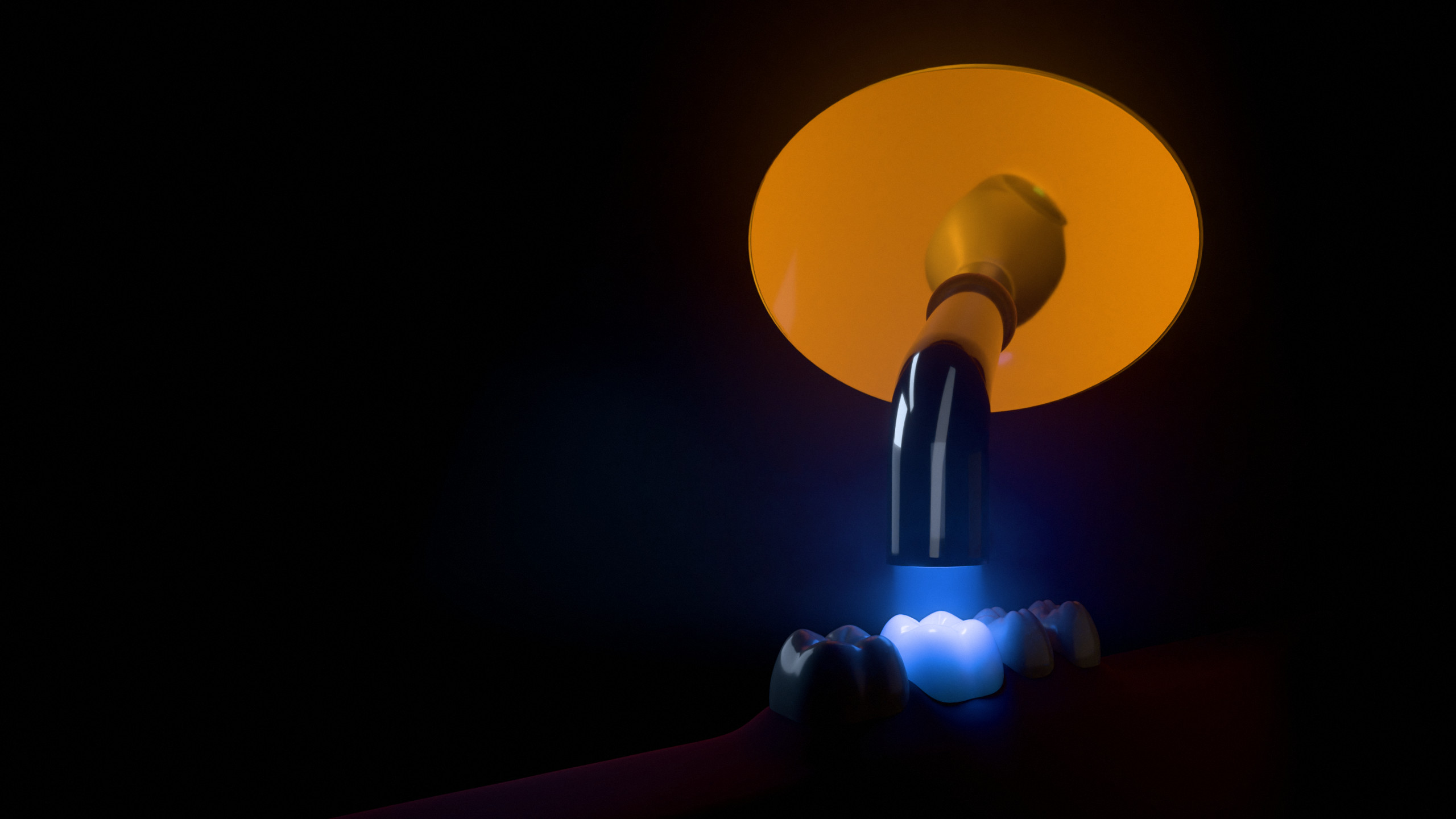 An orange shield on a curing light, seen from the patient’s side, with the beam on a tooth below it.